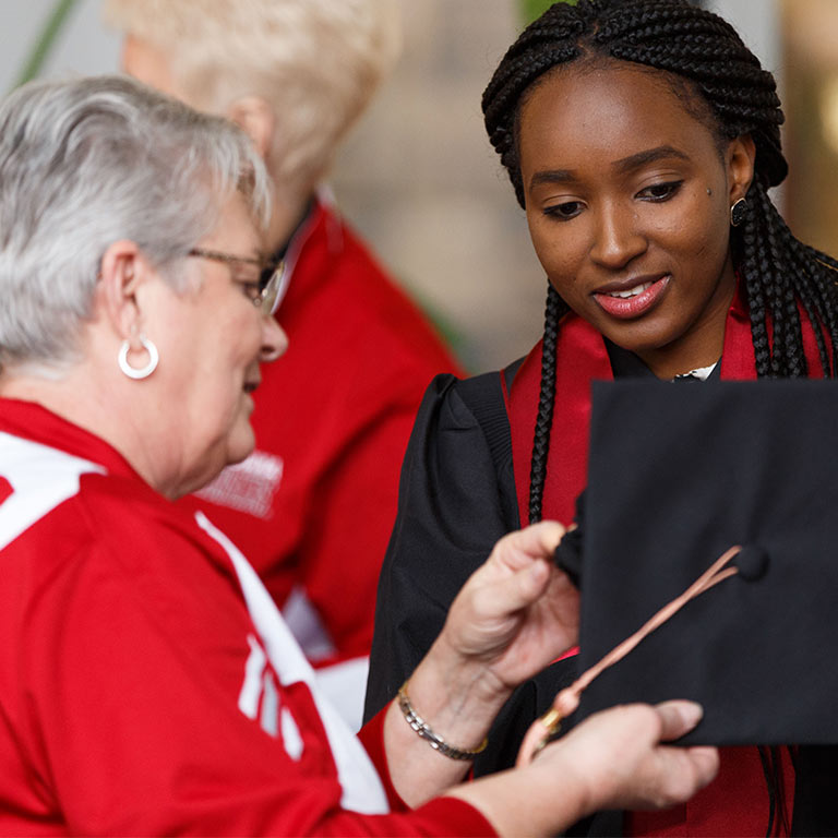 A University Events team member assists a graduate in adjusting a motorboard.